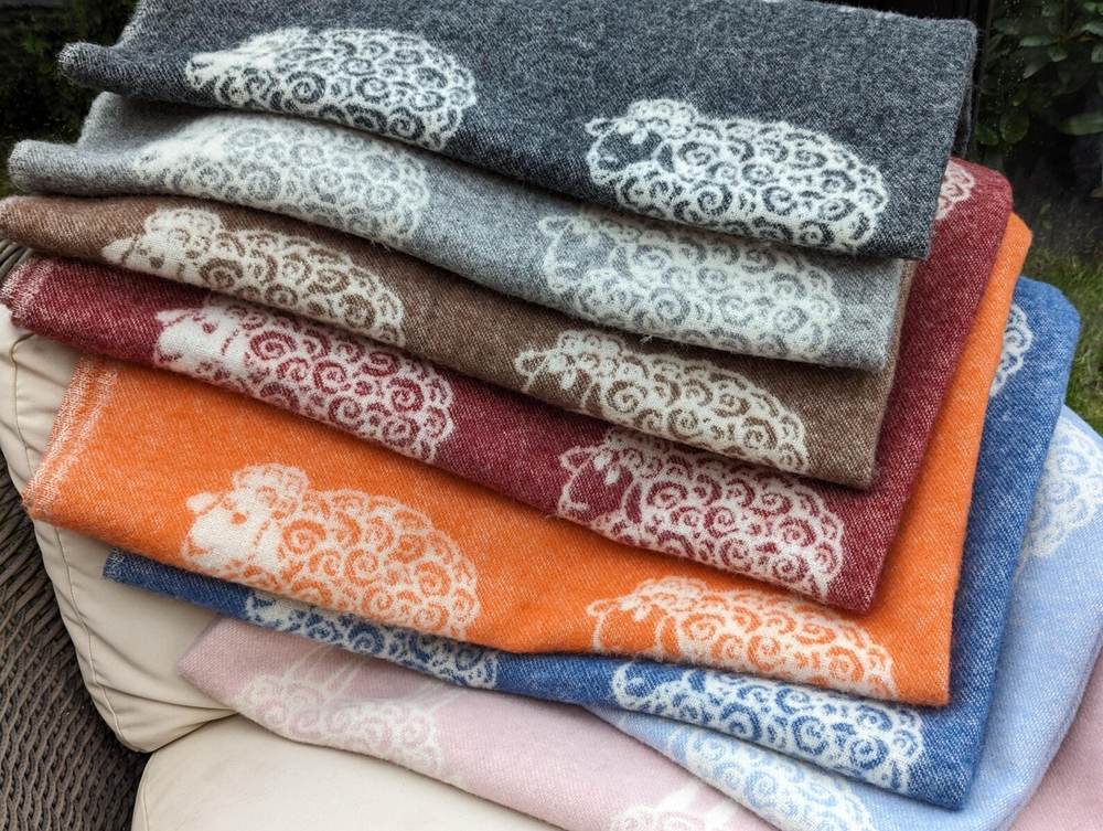 Stack of sheep pattern wool throws in many colours